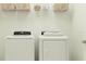 Well-organized laundry area with modern washer, dryer, and shelving for ample storage at 13186 Goldstone Ct, Wimauma, FL 33598