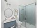Modern bathroom with a walk-in shower and elegant vanity with a round mirror at 1451 Gulf Blvd # 117, Clearwater Beach, FL 33767