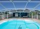 Blue inground pool with sun shelf sits inside a screened-in enclosure, adjacent to patio seating at 14721 Scharber Rd, Dade City, FL 33525