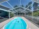 Light blue pool inside screened-in enclosure next to patio with seating, an inviting outdoor living space at 14721 Scharber Rd, Dade City, FL 33525