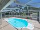 Sunlit pool area with a clear blue pool, patio and screened-in enclosure, ready for relaxation and recreation at 14721 Scharber Rd, Dade City, FL 33525
