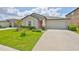 Charming single-story home featuring a well-manicured lawn, tasteful landscaping and an inviting orange front door at 16665 Delia St, Wimauma, FL 33598