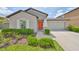 Charming single-story home featuring a well-manicured lawn, tasteful landscaping and an inviting orange front door at 16665 Delia St, Wimauma, FL 33598