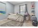 Bedroom featuring a large window, natural light, floral comforter, light blue walls, and gray floors at 3212 E Henry Ave, Tampa, FL 33610