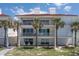 A spacious, three-story condo featuring balconies, palm trees and white Adirondack chairs at 36 Gulf Blvd # 3, Indian Rocks Beach, FL 33785