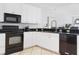 Bright kitchen features white cabinetry, black appliances, and sleek black countertops at 36 Gulf Blvd # 3, Indian Rocks Beach, FL 33785