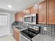 Lovely kitchen with stainless steel appliances, stylish backsplash, granite countertops, and wooden cabinets at 3702 W Reynolds St, Plant City, FL 33563