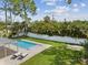 Aerial view of a backyard with a rectangular pool, a covered patio, lounge chairs, and lush green landscaping at 4501 Huntington Ne St, St Petersburg, FL 33703