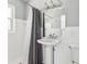 Well-lit bathroom featuring a pedestal sink, shower with grey curtain and updated fixtures at 4501 Huntington Ne St, St Petersburg, FL 33703