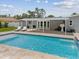 A backyard with a rectangular pool, sun loungers, and a covered patio, all surrounded by a well-maintained lawn at 4501 Huntington Ne St, St Petersburg, FL 33703