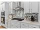 Modern kitchen features sleek white cabinetry, stainless steel appliances, and stylish backsplash, enhancing the home's appeal at 6011 Caldera Ridge Dr, Lithia, FL 33547