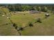 An aerial view showcasing the house, pool, shed, and fenced acreage surrounded by wooded areas at 7509 Hackamore Rd, Zephyrhills, FL 33541