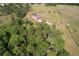 An aerial view showcasing the house, pool, shed, and fenced acreage surrounded by wooded areas at 7509 Hackamore Rd, Zephyrhills, FL 33541