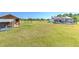 Backyard view featuring the pool, house, and adjacent structure on the expansive, green lawn at 7509 Hackamore Rd, Zephyrhills, FL 33541