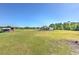 Backyard view featuring the pool, house, and adjacent structure on the expansive, green lawn at 7509 Hackamore Rd, Zephyrhills, FL 33541