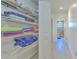 Hallway linen closet with wire shelving, and neatly folded colorful towels and blankets at 7509 Hackamore Rd, Zephyrhills, FL 33541