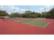Outdoor tennis courts featuring green and red surfaces, surrounded by trees under a clear blue sky at 7520 Sunshine Skyway S Ln # 110, St Petersburg, FL 33711