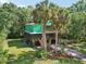 Beautiful two-story green house features a wooden balcony and lush greenery and palm trees around it at 8614 Hibiscus Dr, Tampa, FL 33637