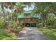 Unique two-story house with a green exterior, lush landscaping, and multiple decks at 8614 Hibiscus Dr, Tampa, FL 33637