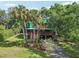 Beautiful two-story green house, with covered parking, and surrounded by lush greenery and palm trees at 8614 Hibiscus Dr, Tampa, FL 33637