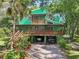 Beautiful two-story green home with a covered parking area and lush gardens with many different plant species at 8614 Hibiscus Dr, Tampa, FL 33637