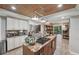 Bright kitchen with a stone island, stainless steel appliances, wooden ceiling, and tile flooring at 8614 Hibiscus Dr, Tampa, FL 33637