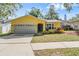 Charming yellow home with a well-manicured lawn and a two-car garage, situated under a beautiful blue sky at 10 Harbor Cove St, Safety Harbor, FL 34695