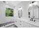 Bright bathroom boasts dual vanity, black fixtures, and natural light from a window overlooking lush greenery at 1135 Wyndham Lakes Dr, Odessa, FL 33556