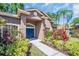 Inviting front entrance of home with a blue door, beautiful landscaping, and well-maintained walkway at 1135 Wyndham Lakes Dr, Odessa, FL 33556