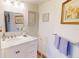 Bathroom with a white vanity, marble countertop, and decorative framed artwork on white walls at 12485 2Nd E St # C103, Treasure Island, FL 33706