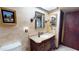 Bathroom featuring elegant vanity, sconces, mirror, textured walls and dark-stained wood door and trim at 12485 2Nd E St # C103, Treasure Island, FL 33706