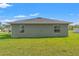 Back exterior view of the house with well-maintained grassy backyard and simple, clean architectural lines at 13193 Paxton Ave, Weeki Wachee, FL 34614