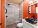 Modern bathroom with glass enclosed shower, sleek vanity, and contrasting orange wall at 140 Brent Cir, Oldsmar, FL 34677