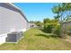 Side yard features lush grass, landscaping, and an air conditioning unit at 14383 Dehaven Ave, Brooksville, FL 34613