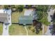 An aerial view of a house with a well-kept yard, driveway, and lush greenery surrounding the property at 1601 Paloma Ln, Dunedin, FL 34698