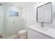 Modern bathroom with a glass shower, tiled floor, and a framed mirror above the sink at 1601 Paloma Ln, Dunedin, FL 34698