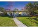 Charming single-story home featuring a well-maintained lawn and inviting walkway under a beautiful dusk sky at 1601 Paloma Ln, Dunedin, FL 34698