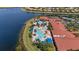 Aerial view of the resort-style community pool and clubhouse with lakeside views and ample seating at 16055 Golden Lakes Dr, Wimauma, FL 33598