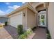 Inviting front entrance with a glass front door, brick walkway, and a two-car garage at 16055 Golden Lakes Dr, Wimauma, FL 33598