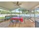 Enclosed patio with ceiling fan, dining set, and comfortable wicker sofa at 1624 Maximilian Dr, Wesley Chapel, FL 33543