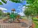 Community playground features a climbing structure with slides, set in a wood chip area surrounded by a white picket fence at 1624 Maximilian Dr, Wesley Chapel, FL 33543