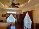 Main bedroom features wood floors, ceiling fan, armoire, and decorative curtains at 17127 Brown Rd, Odessa, FL 33556