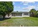 Expansive backyard featuring lush green grass, mature trees, and an enclosed lanai at 1751 Ashton Abbey Rd, Clearwater, FL 33755