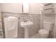 Elegant bathroom featuring a pedestal sink, decorative tile accent, and a modern white toilet at 1751 Ashton Abbey Rd, Clearwater, FL 33755