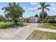 Front exterior of home featuring a driveway, manicured lawn, shade tree, and partial palm tree at 1751 Ashton Abbey Rd, Clearwater, FL 33755