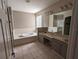 Bathroom featuring dual sinks, a soaking tub, and a large mirror at 19116 Nature Palm Ln, Tampa, FL 33647