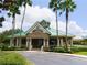Community Club building with green roof, beige exterior, and surrounded by palm trees at 19116 Nature Palm Ln, Tampa, FL 33647
