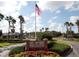 Inviting community entrance featuring a flag, landscaping, and West Meadows signage at 19116 Nature Palm Ln, Tampa, FL 33647