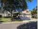 Lovely two-story home with three-car garage, mature trees, manicured lawn, and a concrete driveway in a neighborhood setting at 19116 Nature Palm Ln, Tampa, FL 33647