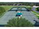 Aerial view of well-maintained tennis courts with a central shaded pavilion and manicured landscaping at 19116 Nature Palm Ln, Tampa, FL 33647
